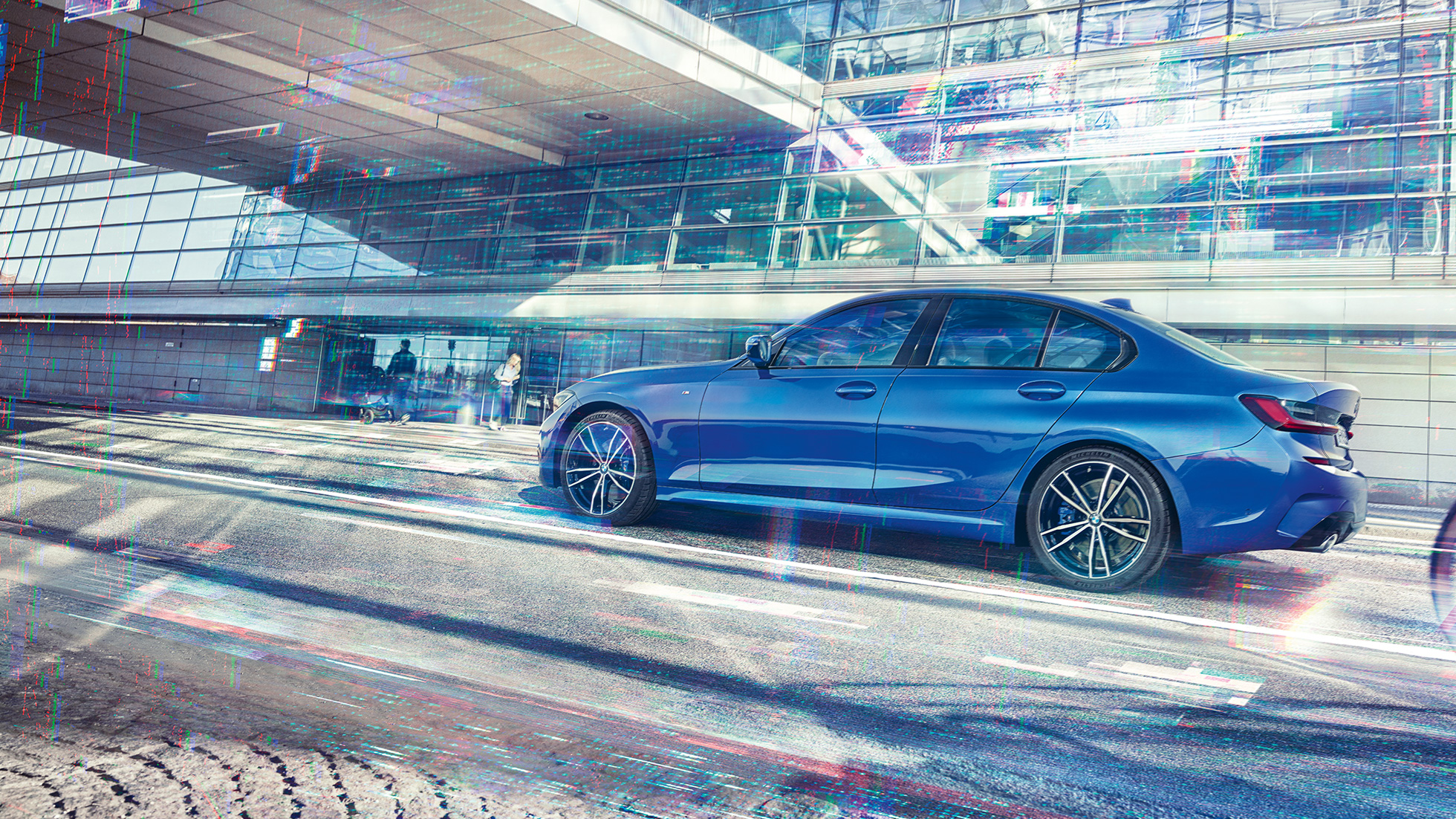 BMW 3 Series Sedan, side view Still shot of the BMW 3 Series Sedan from the side on the day in front of a glass building.