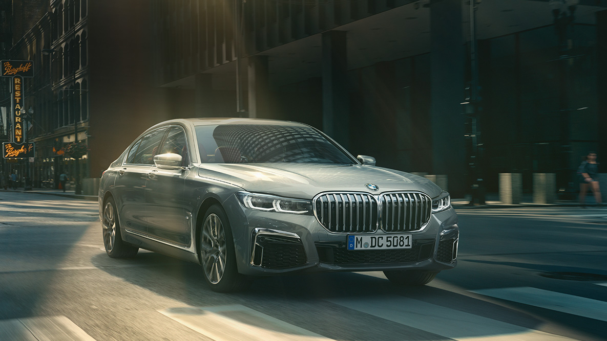 BMW 7 Series Sedan Driving Assistant Driving Assistant: three-quarter front view of BMW 7 Series Sedan driving in front of urban setting