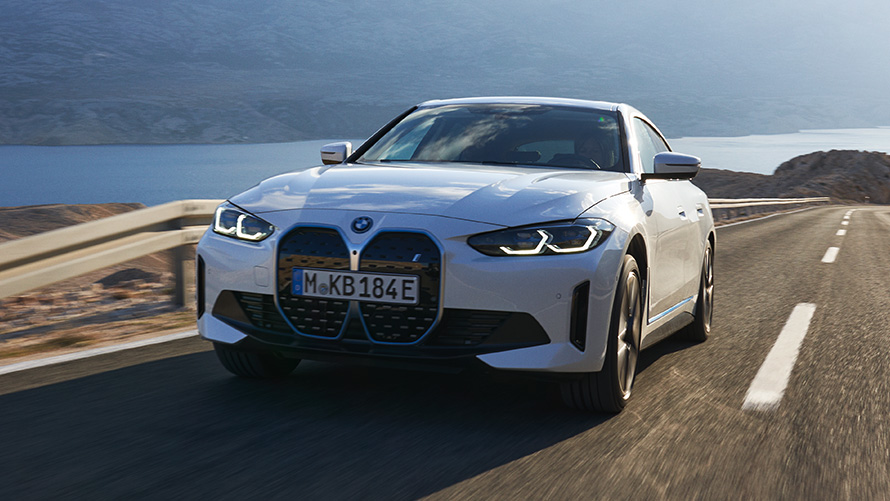 Three-quarter front view BMW i4 eDrive40 G26 2021 driving BMW i4 eDrive40 G26 2021 Mineral White three-quarter front view driving