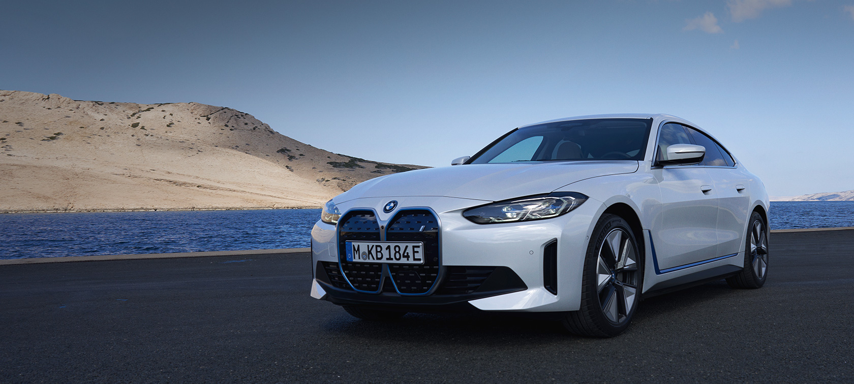 BMW i4 eDrive40 G26 2021 Mineral White three-quarter front view standing in front of lake with hill in background