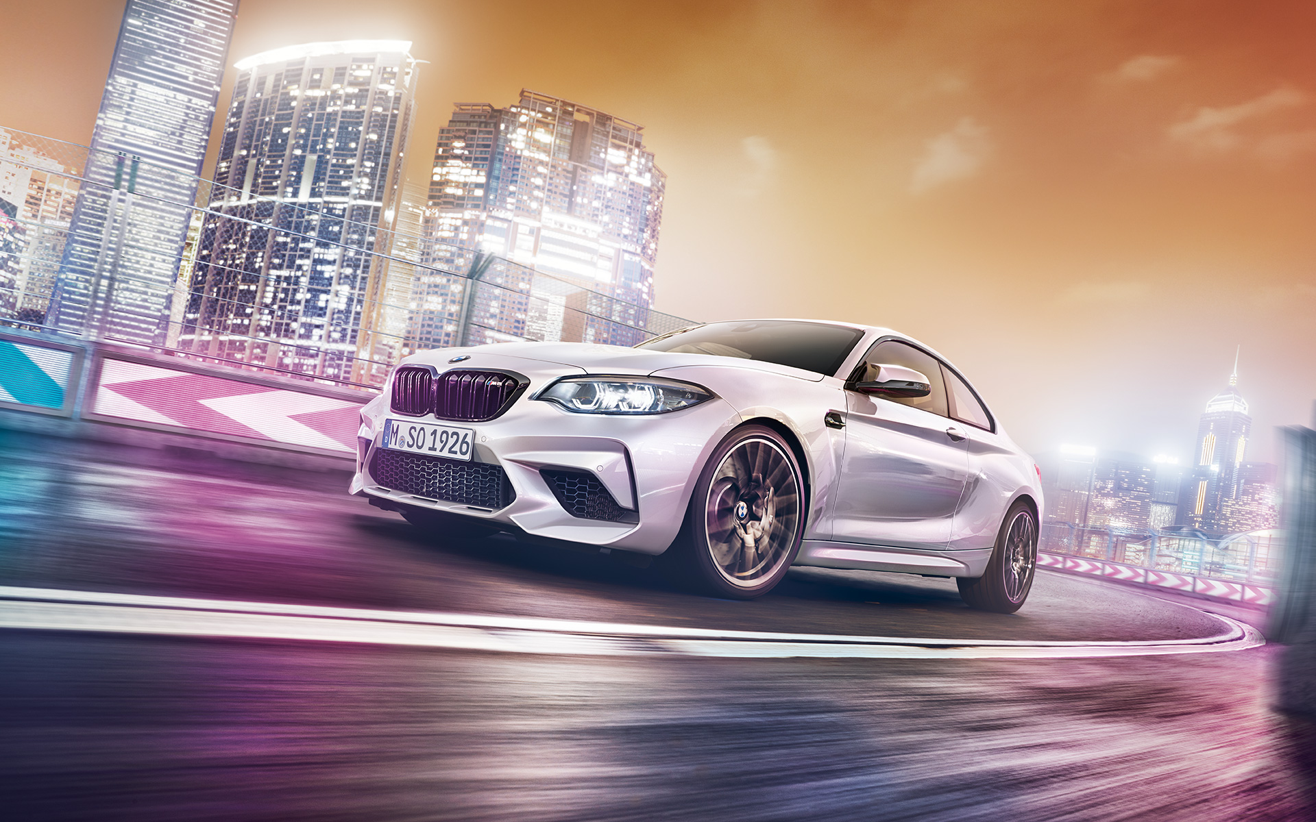 White BMW M2 competition with skyline White BMW M2 Competition driving on race track in front of nocturnal skyline.