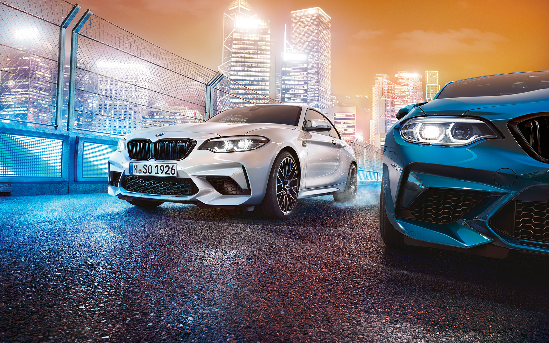 Weißer und blauer BMW M2 Competition in der Frontansicht stehen vor nächtlicher Großstadtkulisse. White and blue BMW M2 Competition in front view standing in front of nocturnal cityscape. Weißer und blauer BMW M2 Competition im Stand White and blue BMW M2 Competition while stationary White and blue BMW M2 Competition in front view standing in front of nocturnal cityscape.