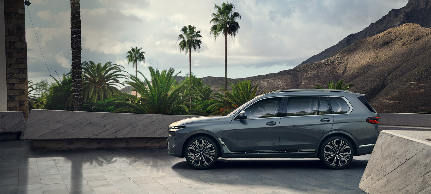 BMW X7 G07 LCI Side View Sparkling Copper Grey metallic BMW X7 G07 LCI Side View standing in front of trees Sparkling Copper Grey metallic